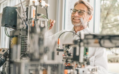 Smiling male technician examining machinery in laboratory